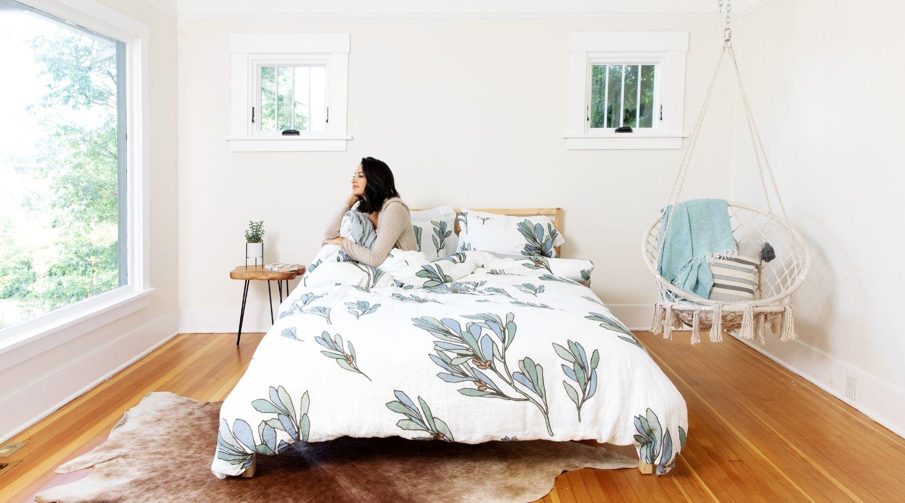 Woman in bed made with organic European flax linen duvet cover set in Scandinavian home looking out the window